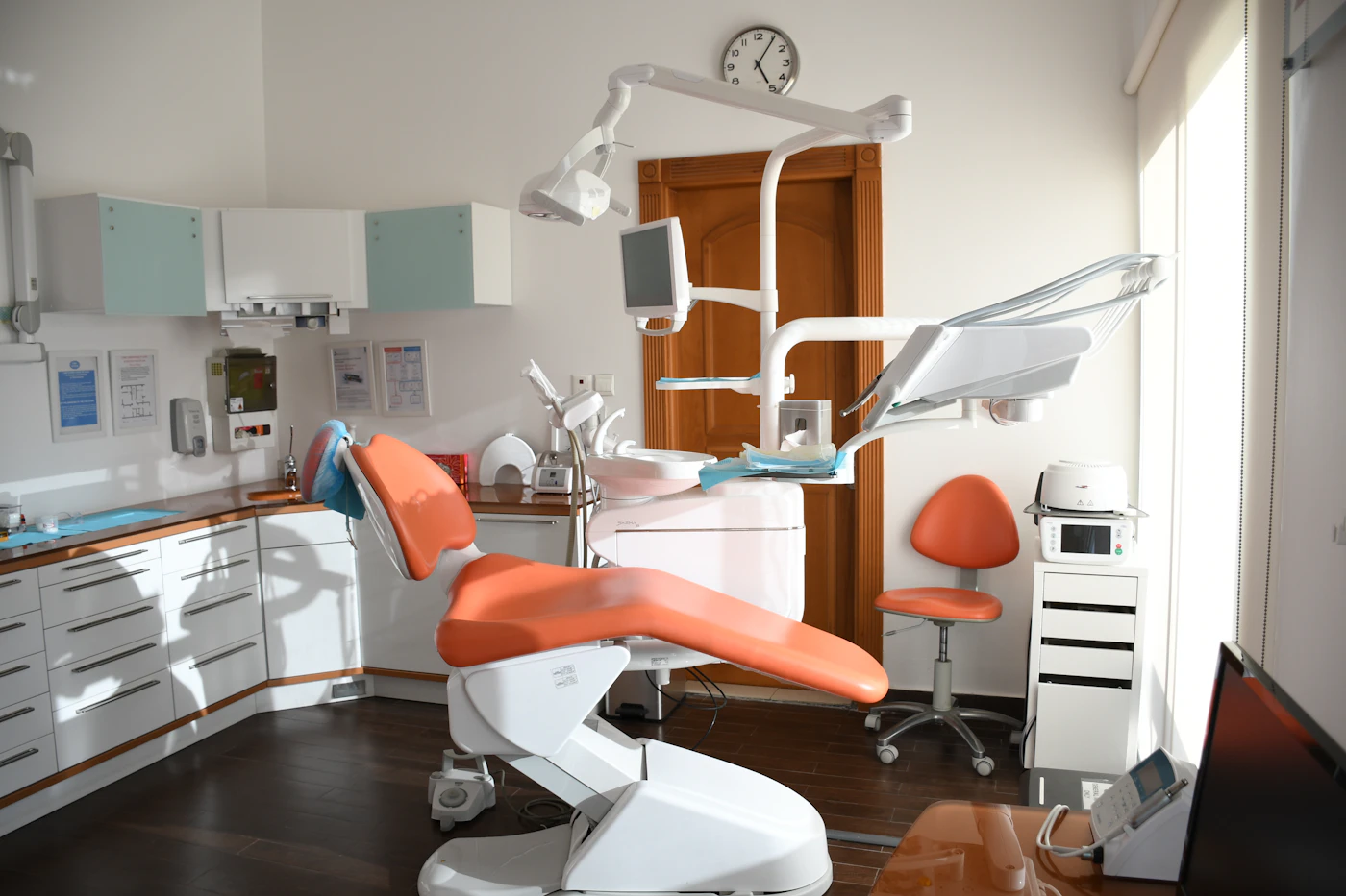 A bright orthodontic treatment room with an orange chair
